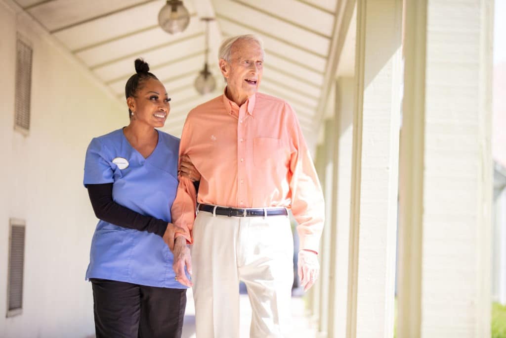 caregiver and senior living resident walking outside