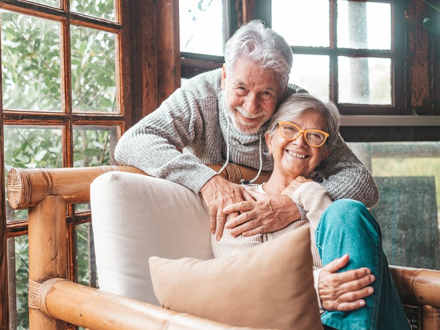 older couple holding each other in front of the window