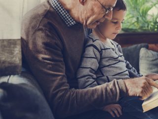 older man reading to little boy