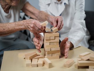 older woman playing jenga for physical therapy