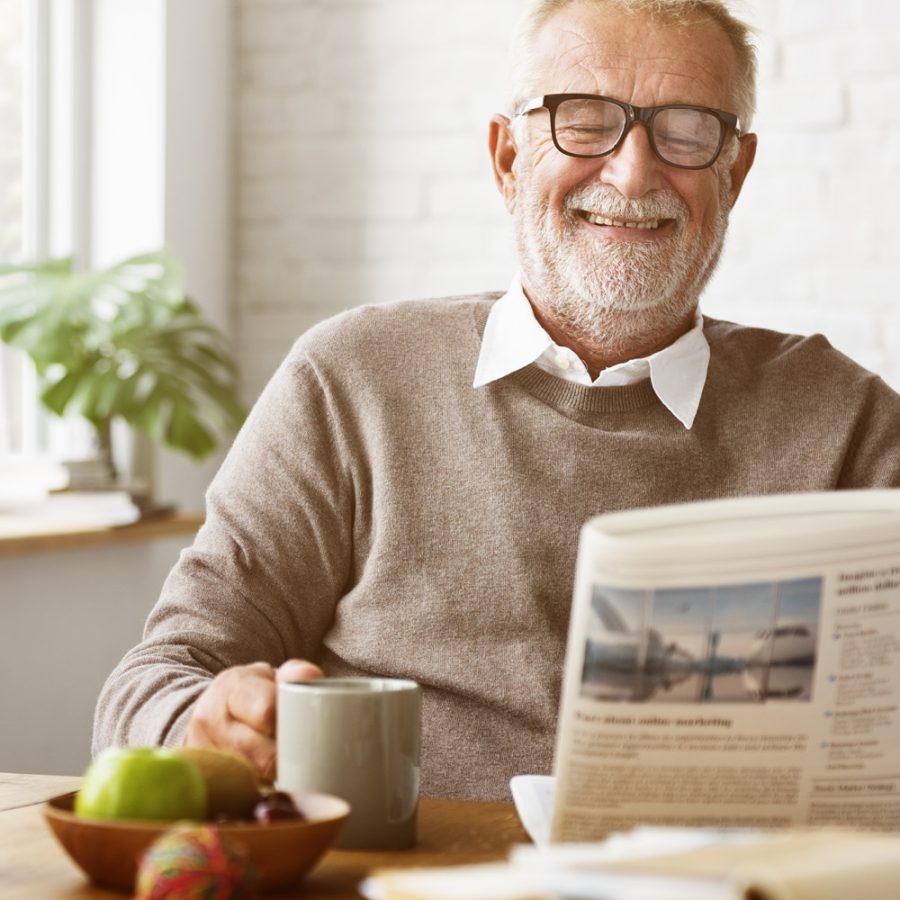 older gentleman drinking coffee and reading the paper